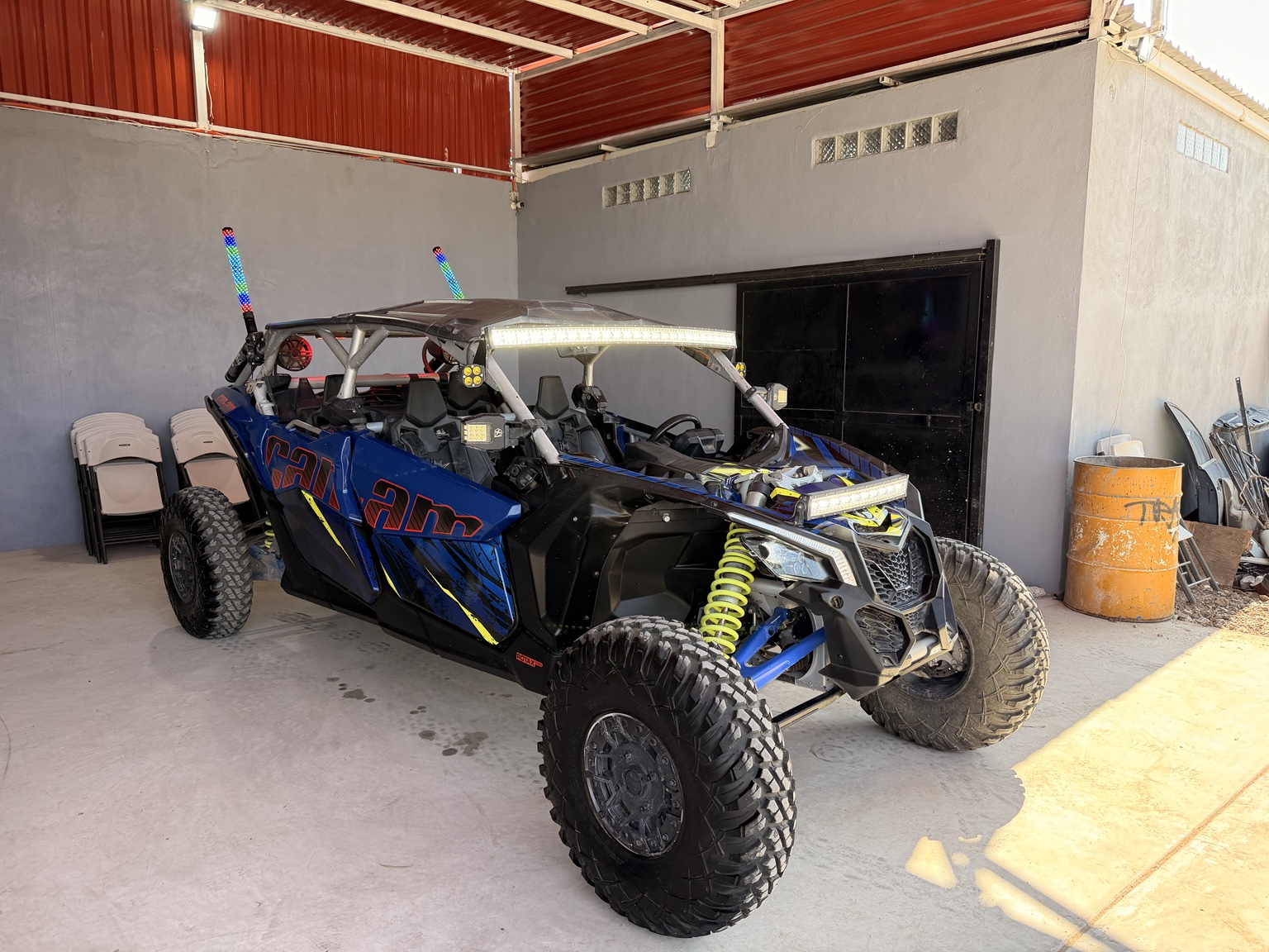 Foto real del Can-Am azul y negro de cuatro plazas que se rifa, con barras LED y suspensión amarilla